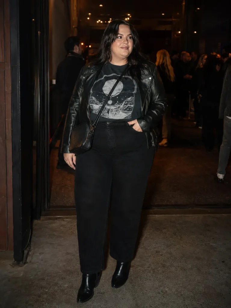 Plus size concert outfit with graphic tee, black jeans, leather look jacket, ankle boots, and crossbody bag